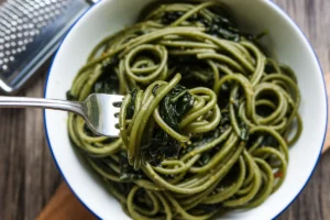 Green spaghetti, or Espagueti Verde, is a colorful and flavorful dish that has found its way into many homes. Known for its creamy green sauce, this green spaghetti recipe uses poblano peppers, cilantro, and cream cheese as its primary ingredients. The combination of these creates a rich, smoky, and tangy sauce that perfectly complements spaghetti. Simple yet versatile, this green spaghetti recipe can fit into many dietary preferences.

This article covers everything you need to know about green spaghetti: its origins, essential ingredients, recipe variations, and tips for making it at home. Whether you’re a first-time cook or an experienced chef, you’ll discover how to make and customize this delicious green spaghetti recipe.

Introduction to Green Spaghetti
Green spaghetti, sometimes referred to as Mexican green spaghetti or Espagueti Verde, stands out because of its vibrant green sauce. The dish's bold color comes from the roasted poblano peppers that form the base of the sauce. These mild chili peppers bring a subtle smokiness and a slight heat to the dish, blending beautifully with creamy elements like cream cheese and sour cream.

Though it’s often compared to Italian pesto pasta due to its color, this green spaghetti recipe has its own distinct flavors. Instead of relying on basil and pine nuts, the green hue and flavor in this dish come from poblanos, cilantro, and dairy. The combination gives the dish a richness that balances out the mild heat of the peppers.

What makes this green spaghetti recipe particularly appealing is its versatility. Green spaghetti works well as either a main dish or a side, making it a perfect choice for family dinners or special gatherings. Additionally, the recipe can be adjusted for dietary restrictions, such as creating vegan green spaghetti or gluten-free green spaghetti.

For a more traditional take on the recipe, Taste of Home offers a delicious green spaghetti recipe that’s easy to follow.

Origins of Green Spaghetti
The roots of green spaghetti lie in Mexican cuisine and Tex-Mex cuisine, where it is known as Espagueti Verde. This dish evolved from a blend of Italian pasta traditions and Mexican ingredients, especially the poblano pepper.

In Mexico, the poblano pepper plays a central role in many dishes, from chiles rellenos to enchiladas. When roasted, poblanos develop a rich, smoky flavor that pairs well with creamy ingredients like Mexican crema or sour cream. This use of roasted poblanos, along with cilantro and cream cheese, gives green spaghetti its unique color and taste.

Although this dish is relatively unknown in Italy, where green pasta often features spinach or basil, the Mexican version gets its signature green color from poblano peppers. The popularity of green spaghetti spread throughout the United States thanks to its presence in Tex-Mex restaurants and Mexican-American homes, leading to the creation of various versions of the green spaghetti recipe.

For a detailed guide on how to prepare the poblano sauce, Delish offers a step-by-step Espagueti Verde recipe.

Main Ingredients of Green Spaghetti
The magic of green spaghetti comes from its combination of simple yet bold ingredients. Here’s a closer look at the key components that make this green spaghetti recipe stand out:

1. Poblano Peppers
Roasted poblano peppers are the heart of this dish. They provide a mild heat and smoky flavor that forms the base of the green sauce. For those who enjoy spicier food, adding serrano or jalapeño peppers can intensify the heat in this green spaghetti recipe.

2. Cream Cheese
Cream cheese gives the sauce its creamy consistency, making it rich and velvety. It blends perfectly with the roasted poblanos, creating a smooth sauce that coats the spaghetti. To lighten the dish, you can substitute low-fat cream cheese or use Greek yogurt.

3. Mexican Crema or Sour Cream
Mexican crema, or sour cream, adds a tangy flavor that balances the richness of the cream cheese. This ingredient also helps neutralize the spiciness of the poblanos, ensuring the sauce is smooth and flavorful.

4. Cilantro
Fresh cilantro brings an herbal, zesty flavor to the sauce. It also enhances the bright green color. For those who don’t enjoy cilantro, you can replace it with parsley or reduce the amount.

5. Garlic and Onion
Garlic and onion add depth and complexity to the sauce. They’re sautéed until fragrant before being blended with the poblanos and other ingredients.

6. Spaghetti
Traditional spaghetti is used for this dish, but you can experiment with whole wheat spaghetti or gluten-free pasta to suit your preferences.

7. Queso Fresco
Crumbled queso fresco is often used as a garnish, adding a light, salty touch to the creamy sauce. It’s a great finishing touch for this green spaghetti recipe.

Step-by-Step Green Spaghetti Recipe
This simple yet delicious green spaghetti recipe is perfect for a weeknight dinner or special occasion. Follow these steps to create this classic Mexican dish.

Ingredients:
3 poblano peppers
1 block of cream cheese
1 cup Mexican crema or sour cream
1 garlic clove
½ onion, chopped
1 bunch of cilantro
1 pound of spaghetti
Salt and pepper to taste
Crumbled queso fresco for garnish
Instructions:
Roast the Poblanos: Roast the poblanos over an open flame or under a broiler until the skins char. After roasting, place them in a bowl covered with plastic wrap and let them steam for 10-15 minutes. Peel off the skins and remove the seeds.

Cook the Spaghetti: Boil the spaghetti in a large pot of salted water according to the package instructions. Drain and set aside.

Make the Sauce: In a blender, combine the roasted poblanos, cream cheese, crema, garlic, onion, and cilantro. Blend until smooth. Season with salt and pepper to taste.

Heat the Sauce: Pour the sauce into a large skillet and heat over medium, making sure it doesn’t boil.

Mix the Pasta and Sauce: Add the cooked spaghetti to the skillet and toss until the pasta is evenly coated with the green sauce.

Serve: Garnish with crumbled queso fresco and a sprinkle of cilantro. Serve immediately and enjoy!

This green spaghetti recipe is easy to make and packed with flavor, making it a perfect choice for any occasion.

Healthier and Vegan Variations of Green Spaghetti
For those looking to make this dish lighter or suitable for special diets, here are a few ways to modify this green spaghetti recipe.

1. Vegan Green Spaghetti
To create a vegan green spaghetti recipe, simply replace the cream cheese and sour cream with plant-based alternatives like cashew cream or vegan cream cheese. You can also omit the queso fresco or use a vegan cheese for the garnish.

2. Low-Fat Green Spaghetti
For a lighter version of this green spaghetti recipe, use low-fat cream cheese and substitute sour cream with Greek yogurt. Using whole wheat spaghetti can increase the fiber content and make the dish more filling.

3. Gluten-Free Green Spaghetti
For a gluten-free green spaghetti recipe, use your favorite gluten-free pasta. Zucchini noodles or other spiralized vegetables can also replace the traditional spaghetti for a low-carb option.

These variations allow you to enjoy the flavors of green spaghetti while catering to your specific dietary needs.

Customizing Green Spaghetti
One of the best aspects of this green spaghetti recipe is its versatility. Here are some ways to customize the dish:

Add Protein: For a more substantial meal, add grilled chicken, shrimp, or even chorizo to your green spaghetti.
Spice It Up: If you like spicy food, add serrano or jalapeño peppers to the sauce for an extra kick.
Add Vegetables: Boost the nutritional value of the dish by including sautéed vegetables like zucchini, mushrooms, or bell peppers.
Experiment with Cheeses: If you don’t have queso fresco on hand, try using cotija, feta, or Parmesan as an alternative.
These options let you put your own spin on the classic green spaghetti recipe, making it perfect for your preferences.

Common Mistakes to Avoid
To ensure your green spaghetti turns out perfect every time, keep these common mistakes in mind:

Not Roasting the Poblanos Fully: Be sure to roast the poblanos until they’re fully blistered. This step brings out the smoky flavor crucial to the dish.
Overcooking the Pasta: Like any pasta dish, green spaghetti tastes best when the spaghetti is cooked al dente. Overcooking can lead to mushy noodles that don’t hold the sauce well.
Curdling the Sauce: Heat the sauce gently to avoid curdling. If the heat is too high, the cream cheese and crema might separate, leading to a grainy sauce.
FAQs About Green Spaghetti
What is the green sauce in green spaghetti made of?
The green sauce in green spaghetti comes primarily from roasted poblano peppers, cilantro, cream cheese, sour cream, and garlic. These ingredients are blended together to create a smooth, creamy sauce.

Can I make green spaghetti without poblanos?
Yes, if poblanos are unavailable, you can substitute them with spinach, kale, or broccoli. These substitutes will provide a green color, but the flavor will differ.

Is green spaghetti spicy?
Green spaghetti is generally mild because of the poblano peppers, which are not very spicy. If you want to add more heat, you can include serrano or jalapeño peppers in the sauce.

Can I make green spaghetti vegan?
Yes, to make a vegan green spaghetti recipe, substitute the dairy ingredients with plant-based alternatives like cashew cream and vegan cream cheese.

Conclusion
This green spaghetti recipe, also known as Espagueti Verde, is a delicious, creamy dish that combines the rich flavor of roasted poblano peppers with creamy sour cream and cream cheese. Whether you follow the traditional recipe or create a variation that suits your dietary preferences, green spaghetti is sure to become a favorite in your household.

For a detailed recipe guide, be sure to check out Delish’s step-by-step Espagueti Verde recipe.

Now that you know how to make this green spaghetti recipe, it’s time to get cooking and enjoy this flavorful dish!