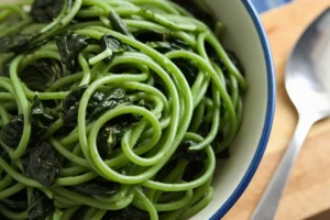 Green spaghetti, or Espagueti Verde, is a colorful and flavorful dish that has found its way into many homes. Known for its creamy green sauce, this green spaghetti recipe uses poblano peppers, cilantro, and cream cheese as its primary ingredients. The combination of these creates a rich, smoky, and tangy sauce that perfectly complements spaghetti. Simple yet versatile, this green spaghetti recipe can fit into many dietary preferences.

This article covers everything you need to know about green spaghetti: its origins, essential ingredients, recipe variations, and tips for making it at home. Whether you’re a first-time cook or an experienced chef, you’ll discover how to make and customize this delicious green spaghetti recipe.

Introduction to Green Spaghetti
Green spaghetti, sometimes referred to as Mexican green spaghetti or Espagueti Verde, stands out because of its vibrant green sauce. The dish's bold color comes from the roasted poblano peppers that form the base of the sauce. These mild chili peppers bring a subtle smokiness and a slight heat to the dish, blending beautifully with creamy elements like cream cheese and sour cream.

Though it’s often compared to Italian pesto pasta due to its color, this green spaghetti recipe has its own distinct flavors. Instead of relying on basil and pine nuts, the green hue and flavor in this dish come from poblanos, cilantro, and dairy. The combination gives the dish a richness that balances out the mild heat of the peppers.

What makes this green spaghetti recipe particularly appealing is its versatility. Green spaghetti works well as either a main dish or a side, making it a perfect choice for family dinners or special gatherings. Additionally, the recipe can be adjusted for dietary restrictions, such as creating vegan green spaghetti or gluten-free green spaghetti.

For a more traditional take on the recipe, Taste of Home offers a delicious green spaghetti recipe that’s easy to follow.

Origins of Green Spaghetti
The roots of green spaghetti lie in Mexican cuisine and Tex-Mex cuisine, where it is known as Espagueti Verde. This dish evolved from a blend of Italian pasta traditions and Mexican ingredients, especially the poblano pepper.

In Mexico, the poblano pepper plays a central role in many dishes, from chiles rellenos to enchiladas. When roasted, poblanos develop a rich, smoky flavor that pairs well with creamy ingredients like Mexican crema or sour cream. This use of roasted poblanos, along with cilantro and cream cheese, gives green spaghetti its unique color and taste.

Although this dish is relatively unknown in Italy, where green pasta often features spinach or basil, the Mexican version gets its signature green color from poblano peppers. The popularity of green spaghetti spread throughout the United States thanks to its presence in Tex-Mex restaurants and Mexican-American homes, leading to the creation of various versions of the green spaghetti recipe.

For a detailed guide on how to prepare the poblano sauce, Delish offers a step-by-step Espagueti Verde recipe.

Main Ingredients of Green Spaghetti
The magic of green spaghetti comes from its combination of simple yet bold ingredients. Here’s a closer look at the key components that make this green spaghetti recipe stand out:

1. Poblano Peppers
Roasted poblano peppers are the heart of this dish. They provide a mild heat and smoky flavor that forms the base of the green sauce. For those who enjoy spicier food, adding serrano or jalapeño peppers can intensify the heat in this green spaghetti recipe.

2. Cream Cheese
Cream cheese gives the sauce its creamy consistency, making it rich and velvety. It blends perfectly with the roasted poblanos, creating a smooth sauce that coats the spaghetti. To lighten the dish, you can substitute low-fat cream cheese or use Greek yogurt.

3. Mexican Crema or Sour Cream
Mexican crema, or sour cream, adds a tangy flavor that balances the richness of the cream cheese. This ingredient also helps neutralize the spiciness of the poblanos, ensuring the sauce is smooth and flavorful.

4. Cilantro
Fresh cilantro brings an herbal, zesty flavor to the sauce. It also enhances the bright green color. For those who don’t enjoy cilantro, you can replace it with parsley or reduce the amount.

5. Garlic and Onion
Garlic and onion add depth and complexity to the sauce. They’re sautéed until fragrant before being blended with the poblanos and other ingredients.

6. Spaghetti
Traditional spaghetti is used for this dish, but you can experiment with whole wheat spaghetti or gluten-free pasta to suit your preferences.

7. Queso Fresco
Crumbled queso fresco is often used as a garnish, adding a light, salty touch to the creamy sauce. It’s a great finishing touch for this green spaghetti recipe.

Step-by-Step Green Spaghetti Recipe
This simple yet delicious green spaghetti recipe is perfect for a weeknight dinner or special occasion. Follow these steps to create this classic Mexican dish.

Ingredients:
3 poblano peppers
1 block of cream cheese
1 cup Mexican crema or sour cream
1 garlic clove
½ onion, chopped
1 bunch of cilantro
1 pound of spaghetti
Salt and pepper to taste
Crumbled queso fresco for garnish
Instructions:
Roast the Poblanos: Roast the poblanos over an open flame or under a broiler until the skins char. After roasting, place them in a bowl covered with plastic wrap and let them steam for 10-15 minutes. Peel off the skins and remove the seeds.

Cook the Spaghetti: Boil the spaghetti in a large pot of salted water according to the package instructions. Drain and set aside.

Make the Sauce: In a blender, combine the roasted poblanos, cream cheese, crema, garlic, onion, and cilantro. Blend until smooth. Season with salt and pepper to taste.

Heat the Sauce: Pour the sauce into a large skillet and heat over medium, making sure it doesn’t boil.

Mix the Pasta and Sauce: Add the cooked spaghetti to the skillet and toss until the pasta is evenly coated with the green sauce.

Serve: Garnish with crumbled queso fresco and a sprinkle of cilantro. Serve immediately and enjoy!

This green spaghetti recipe is easy to make and packed with flavor, making it a perfect choice for any occasion.

Healthier and Vegan Variations of Green Spaghetti
For those looking to make this dish lighter or suitable for special diets, here are a few ways to modify this green spaghetti recipe.

1. Vegan Green Spaghetti
To create a vegan green spaghetti recipe, simply replace the cream cheese and sour cream with plant-based alternatives like cashew cream or vegan cream cheese. You can also omit the queso fresco or use a vegan cheese for the garnish.

2. Low-Fat Green Spaghetti
For a lighter version of this green spaghetti recipe, use low-fat cream cheese and substitute sour cream with Greek yogurt. Using whole wheat spaghetti can increase the fiber content and make the dish more filling.

3. Gluten-Free Green Spaghetti
For a gluten-free green spaghetti recipe, use your favorite gluten-free pasta. Zucchini noodles or other spiralized vegetables can also replace the traditional spaghetti for a low-carb option.

These variations allow you to enjoy the flavors of green spaghetti while catering to your specific dietary needs.

Customizing Green Spaghetti
One of the best aspects of this green spaghetti recipe is its versatility. Here are some ways to customize the dish:

Add Protein: For a more substantial meal, add grilled chicken, shrimp, or even chorizo to your green spaghetti.
Spice It Up: If you like spicy food, add serrano or jalapeño peppers to the sauce for an extra kick.
Add Vegetables: Boost the nutritional value of the dish by including sautéed vegetables like zucchini, mushrooms, or bell peppers.
Experiment with Cheeses: If you don’t have queso fresco on hand, try using cotija, feta, or Parmesan as an alternative.
These options let you put your own spin on the classic green spaghetti recipe, making it perfect for your preferences.

Common Mistakes to Avoid
To ensure your green spaghetti turns out perfect every time, keep these common mistakes in mind:

Not Roasting the Poblanos Fully: Be sure to roast the poblanos until they’re fully blistered. This step brings out the smoky flavor crucial to the dish.
Overcooking the Pasta: Like any pasta dish, green spaghetti tastes best when the spaghetti is cooked al dente. Overcooking can lead to mushy noodles that don’t hold the sauce well.
Curdling the Sauce: Heat the sauce gently to avoid curdling. If the heat is too high, the cream cheese and crema might separate, leading to a grainy sauce.
FAQs About Green Spaghetti
What is the green sauce in green spaghetti made of?
The green sauce in green spaghetti comes primarily from roasted poblano peppers, cilantro, cream cheese, sour cream, and garlic. These ingredients are blended together to create a smooth, creamy sauce.

Can I make green spaghetti without poblanos?
Yes, if poblanos are unavailable, you can substitute them with spinach, kale, or broccoli. These substitutes will provide a green color, but the flavor will differ.

Is green spaghetti spicy?
Green spaghetti is generally mild because of the poblano peppers, which are not very spicy. If you want to add more heat, you can include serrano or jalapeño peppers in the sauce.

Can I make green spaghetti vegan?
Yes, to make a vegan green spaghetti recipe, substitute the dairy ingredients with plant-based alternatives like cashew cream and vegan cream cheese.

Conclusion
This green spaghetti recipe, also known as Espagueti Verde, is a delicious, creamy dish that combines the rich flavor of roasted poblano peppers with creamy sour cream and cream cheese. Whether you follow the traditional recipe or create a variation that suits your dietary preferences, green spaghetti is sure to become a favorite in your household.

For a detailed recipe guide, be sure to check out Delish’s step-by-step Espagueti Verde recipe.

Now that you know how to make this green spaghetti recipe, it’s time to get cooking and enjoy this flavorful dish!